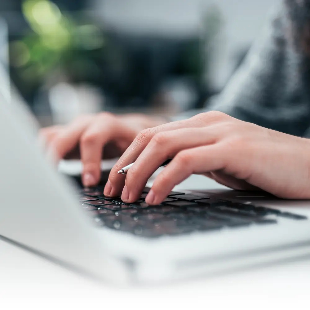 Hands of a woman typing at a keyboard, taking a BecomingX corporate learning course