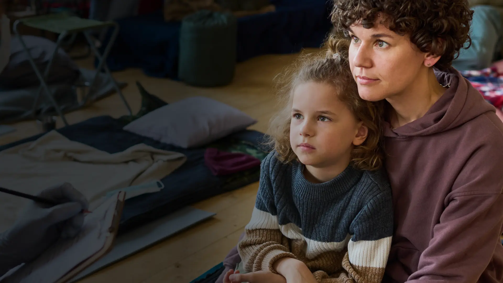 Female refugee sits with her daughter in temporary accommodation.