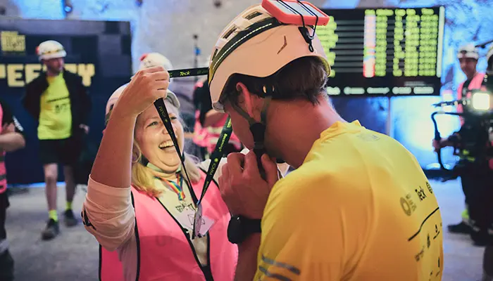 Alexis Rose of BecomingX puts a medal around the neck of a runner in the World's Deepest Marathon