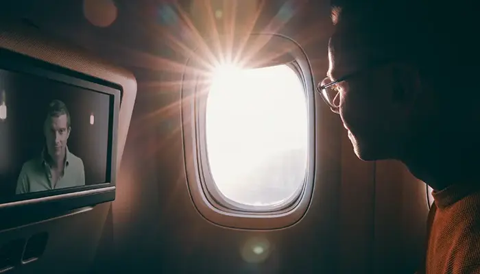 A man on a plane watching the Bear Grylls BecomingX film